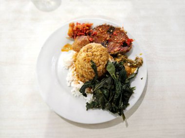 Nasi Padang ve yanında sebze ve biber soslu Balado koçanı.