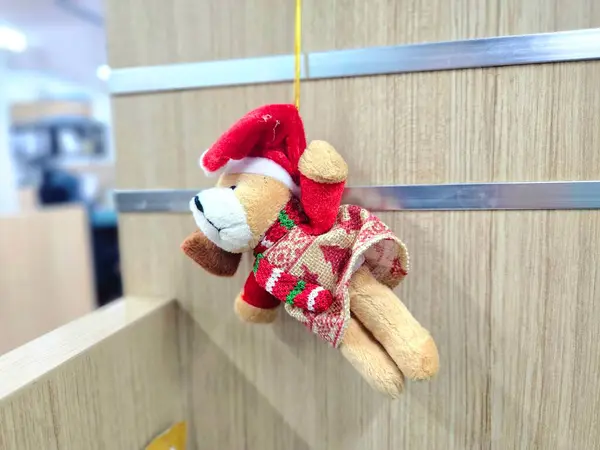 Noel 'i ofis masasında kutlamak için Noel Baba kıyafeti giyen sevimli ayıcığı asmak.