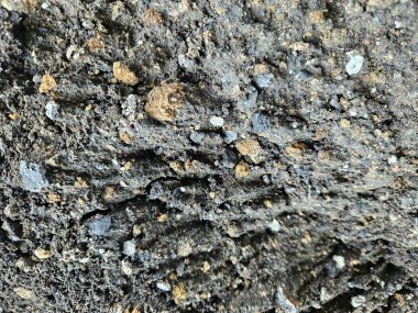 Nemden parlak bir bitişe sahip desenli siyah kum yüzeyi, ince taneleri vurguluyor ve organik güzellikler sergiliyor.