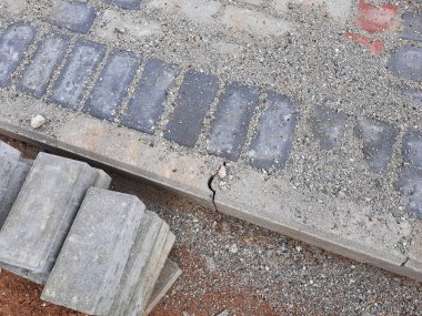 Yapım aşamasındaki dekoratif tuğla kaldırım tasarımına yakın plan, zıt kırmızı ve gri bloklar