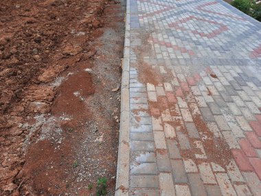 Yapım aşamasındaki dekoratif tuğla kaldırım tasarımına yakın plan, zıt kırmızı ve gri bloklar