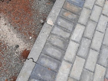 Yapım aşamasındaki dekoratif tuğla kaldırım tasarımına yakın plan, zıt kırmızı ve gri bloklar