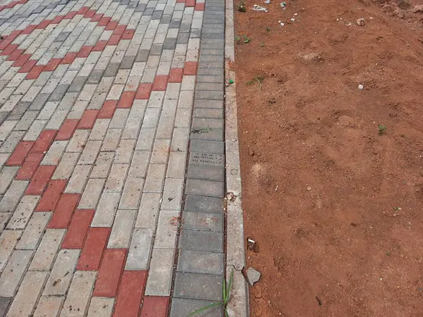 Yapım aşamasındaki dekoratif tuğla kaldırım tasarımına yakın plan, zıt kırmızı ve gri bloklar