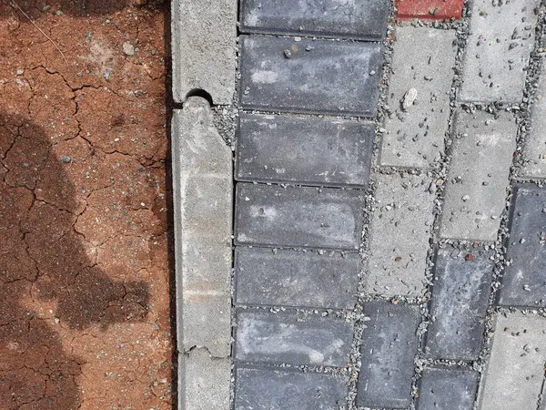 Yapım aşamasındaki dekoratif tuğla kaldırım tasarımına yakın plan, zıt kırmızı ve gri bloklar
