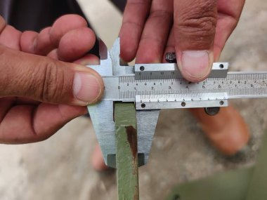 Metal kirişi ölçmek için kalibre kullanan ellerin yakın çekimi..