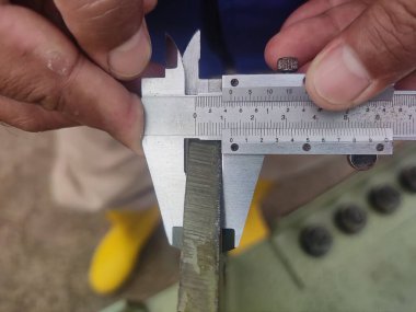 Metal kirişi ölçmek için kalibre kullanan ellerin yakın çekimi..