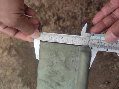 Metal kirişi ölçmek için kalibre kullanan ellerin yakın çekimi..