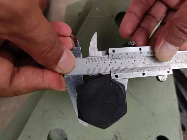 Metal kirişi ölçmek için kalibre kullanan ellerin yakın çekimi..