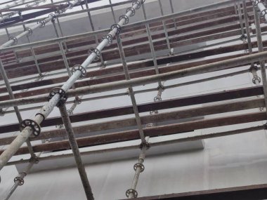 İnşaat alanındaki metal iskelenin düşük açılı görüntüsü, iskeletin karmaşık detaylarını gösteriyor