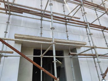 İnşaat halindeki beton bir binanın metal iskelesi, düşük açıyla çekilmiş.