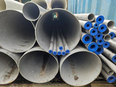 İnşaat alanında mavi koruyucu kapaklı büyük endüstriyel paslanmaz çelik borular.