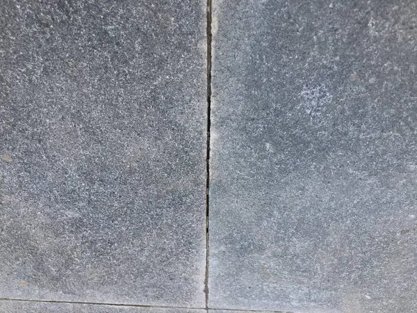 İnce çatlaklar ve yıpranmış yüzeyi olan sert beton zemin, arka planlar, tasarım dokuları veya mimari referanslar için mükemmel.
