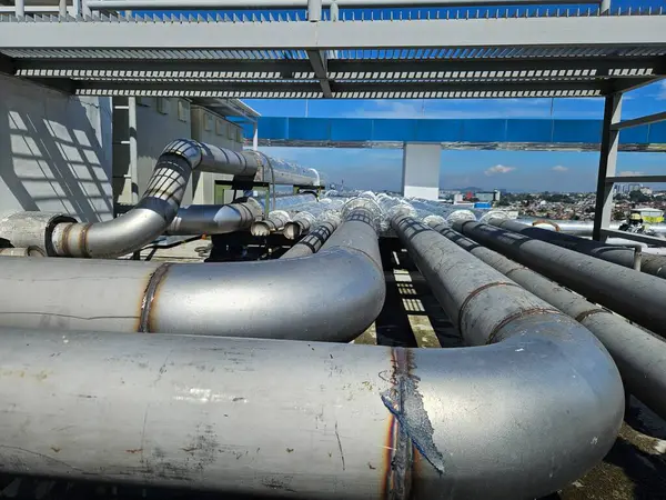 Çatıdaki havalandırma sistemi için paslanmaz çelik boru hattı şebekesi şehir binalarının arka planına karşı doğrudan güneş ışığı altında. Kentsel sanayi ve inşaat temaları için mükemmel