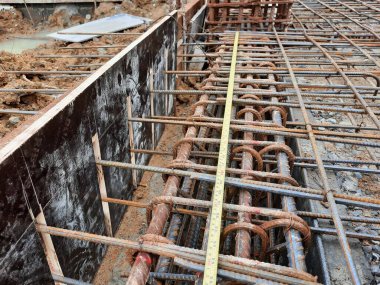 Düzeni ve takviye uzunluğunu doğrulamak için bant ölçümlü inşaat demirleri yapısı yatay olarak gerildi. İnşaat mühendisliği, yapısal işler, inşaat teftişi, ölçüm teması