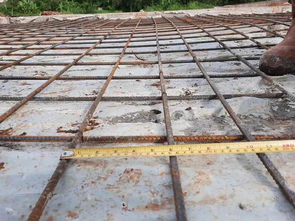 Düzeni ve takviye uzunluğunu doğrulamak için bant ölçümlü inşaat demirleri yapısı yatay olarak gerildi. İnşaat mühendisliği, yapısal işler, inşaat teftişi, ölçüm teması
