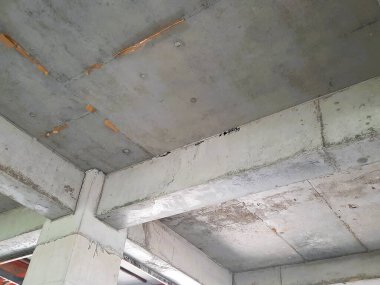 Tamamlanmamış bir binada güçlendirilmiş beton sütun ve kiriş yapısı biçimsel izler ve yapısal hizalama gösteriyor. Beton yapı, inşaat mühendisliği ve inşaat ilerleme teması için uygun