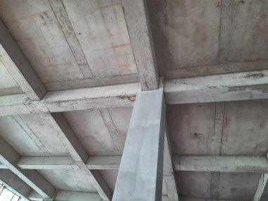 Tamamlanmamış bir binada güçlendirilmiş beton sütun ve kiriş yapısı biçimsel izler ve yapısal hizalama gösteriyor. Beton yapı, inşaat mühendisliği ve inşaat ilerleme teması için uygun