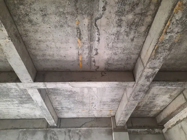 Tamamlanmamış bir binada güçlendirilmiş beton sütun ve kiriş yapısı biçimsel izler ve yapısal hizalama gösteriyor. Beton yapı, inşaat mühendisliği ve inşaat ilerleme teması için uygun