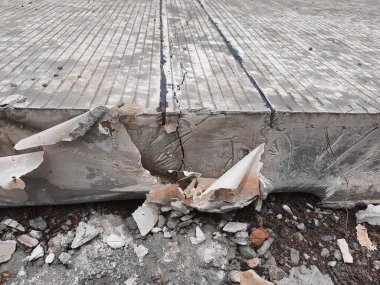 Görünür çatlaklara ve molozlara sahip hasarlı betonun yakın çekimi, inşaat veya altyapı temaları için ideal