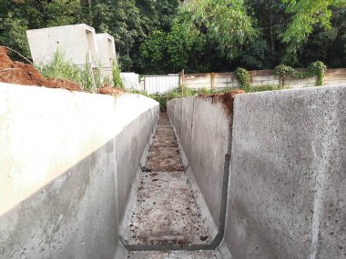 İnşaat mühendisliği için toprak ve yapısal detayları gösteren beton su drenaj sistemi yapım aşamasında