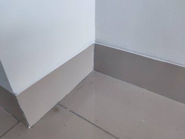 Temiz bir iç duvar köşesi, parlak seramik etek ve beyaz duvar boyası. İç tasarım, döşeme, gayrimenkul ya da mimari detay gibi konular için ideal