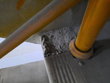 Aktif bir inşaat alanında merdiven köşesinde toz ve enkaz birikiyor. Endüstriyel güvenlik ve site teftiş temaları için uygundur