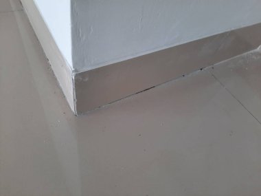 Temiz bir iç duvar köşesi, parlak seramik etek ve beyaz duvar boyası. İç tasarım, döşeme, gayrimenkul ya da mimari detay gibi konular için ideal