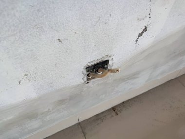 Duvar soketinden çıkan açıkta kalmış kablolarla tamamlanmamış elektrik tesisatı. Elektrik tesisatı, ev yenileme, elektrik güvenliği ve inşaat konuları için uygun