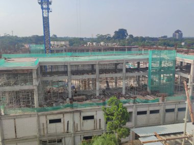 Geliştirme alanı güçlendirilmiş yapılar, yeşil güvenlik ağı, ve kule vinci, altyapı sahnesi. İnşaat ilerlemesi, gayrimenkul geliştirme ve kentsel altyapı temaları için uygun