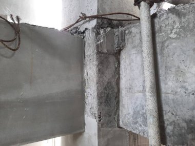 Büyük boru ve duvar lekeleri ile beton muhafaza köşesi, bina drenaj sistemini ve ihmal edilmiş bakım koşullarını temsil ediyor