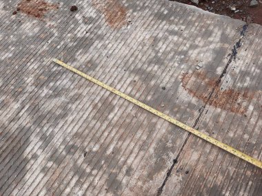 Düz olmayan beton zemine yerleştirilmiş bant ölçüsü, bina hazırlığı, araştırma veya ölçüm konsepti görselleri için ideal