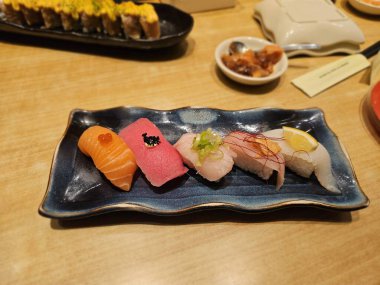 Japon yemek görselleri, menü fotoğrafçılığı veya yemek deneyimi reklamları için harika olan mavi tabakta renkli nigiri suşi seti sergilenmektedir.