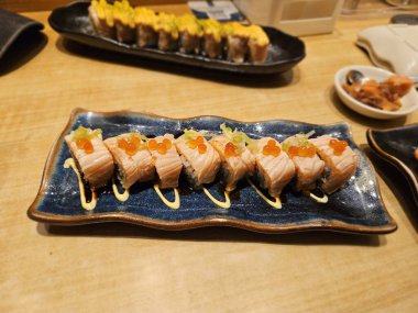 Seramik tabağa dizilmiş ızgara soslu suşi ruloları restoran reklamları, Asya yemeği içeriği ya da paket servis menüleri için ideal.