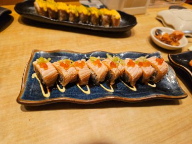 Seramik tabağa dizilmiş ızgara soslu suşi ruloları restoran reklamları, Asya yemeği içeriği ya da paket servis menüleri için ideal.