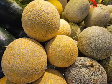 Taze sebze reyonunda yığılmış çeşitli kavunlar. Tarım, yaz meyve temaları veya pazar afişleri için harika