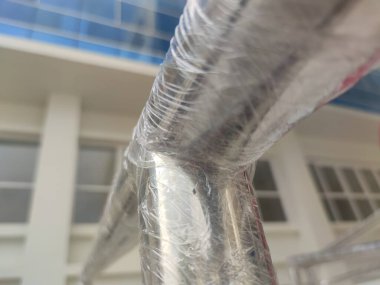 Plastik ambalajla kaplı paslanmaz çelik korkulukların ayrıntılı görünümü, genellikle yeni inşaat alanlarında veya endüstriyel proje tesislerinde görülür