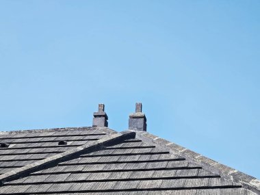 Açık gökyüzüne uzanan ikiz bacalı çatı manzarası mimari arka planlar için basitlik, simetri ve modern yapı sergiliyor.