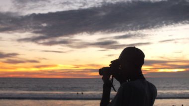 Canlı bir plaj günbatımına karşı fotoğrafçı silueti, seyahat, fotoğraf ve ilham verici görseller için uygun.