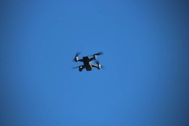 Uçuşun ortasında mavi gökyüzüne karşı bir dron, teknoloji, hava fotoğrafçılığı, gözetleme ve yenilik kavramları için ideal.