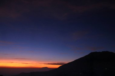 Renkli gündoğumu gökyüzünün altında bir dağın silueti seyahat, macera, doğa ve manzara temalarına uygundur.