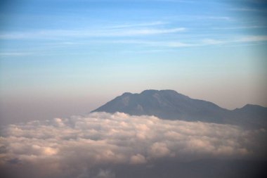 Bulutların üzerindeki görkemli dağ zirveleri seyahat, macera ve doğa fotoğrafçılığı temaları için idealdir.