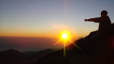 Büyüleyici bir gündoğumunu gösteren bir dağ yürüyüşçüsünün silueti motivasyon posterleri, seyahat promosyonları ya da macera temalı tasarımlar için mükemmel.