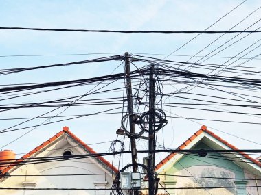 Yerleşim bölgelerinde elektrik kabloları, birbirine dolanmış kablolar ve çatıların ortasındaki iletişim altyapısı kentsel karmaşıklığı gösteriyor.