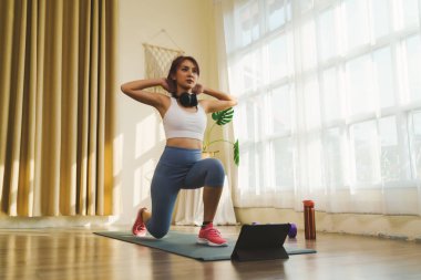 Spor kıyafetleri ve spor ayakkabıları giyen Asyalı bir kadın evde yağ yakmak için egzersiz yapıyor, yoga minderinde vücudu güçlendiriyor, evde sağlıklı bir yaşam tarzı var..