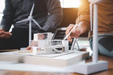 İki mühendis tasarım uzmanı, modelle çalışarak elektrik üretmek ve güneş paneli numunesi üretmek için çatı katında saf enerji kullanımı ve güneş panelleri kurmayı hesaplamayı tartışıyor.