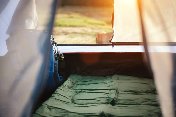Inside camping tent with a backpack and green sleeping bag prepare to lie in soft sunlight and fair in the tents