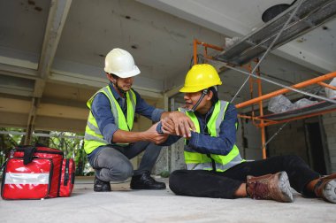 İnşaat alanındaki inşaat işçisinin iş yerinde ilk yardım kazası. Dirsek kazası, Foreman ilk yardım çantası ile çalışan kazasına yardım ediyor..