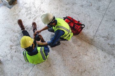 İnşaat alanındaki inşaat işçisinin iş yerinde ilk yardım kazası. Diz kazası ve bilek ağrısı, Foreman çalışanlara ilk yardım çantası için yardım ediyor..