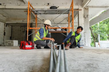 İnşaat işyerindeki kaza, elektrik metal boru, masum bir inşaatçının bacağına, Foreman 'ın inşaat alanında yaralanan meslektaşına ya da inşaatçıya ilk yardım çantasıyla yardım etmesi.