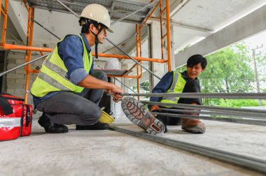 İnşaat işyerindeki kaza, elektrik metal boru, masum bir inşaatçının bacağına, Foreman 'ın inşaat alanında yaralanan meslektaşına ya da inşaatçıya ilk yardım çantasıyla yardım etmesi.